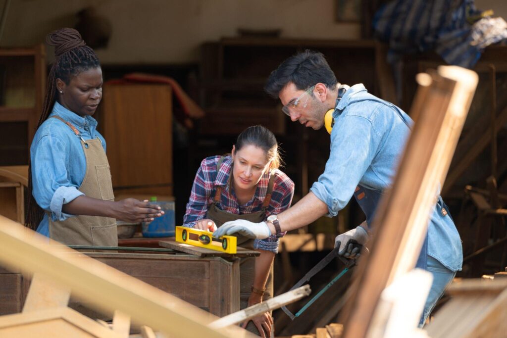 Team of barn repair contractors measuring and planning pole barn restoration using traditional tools and modern techniques.