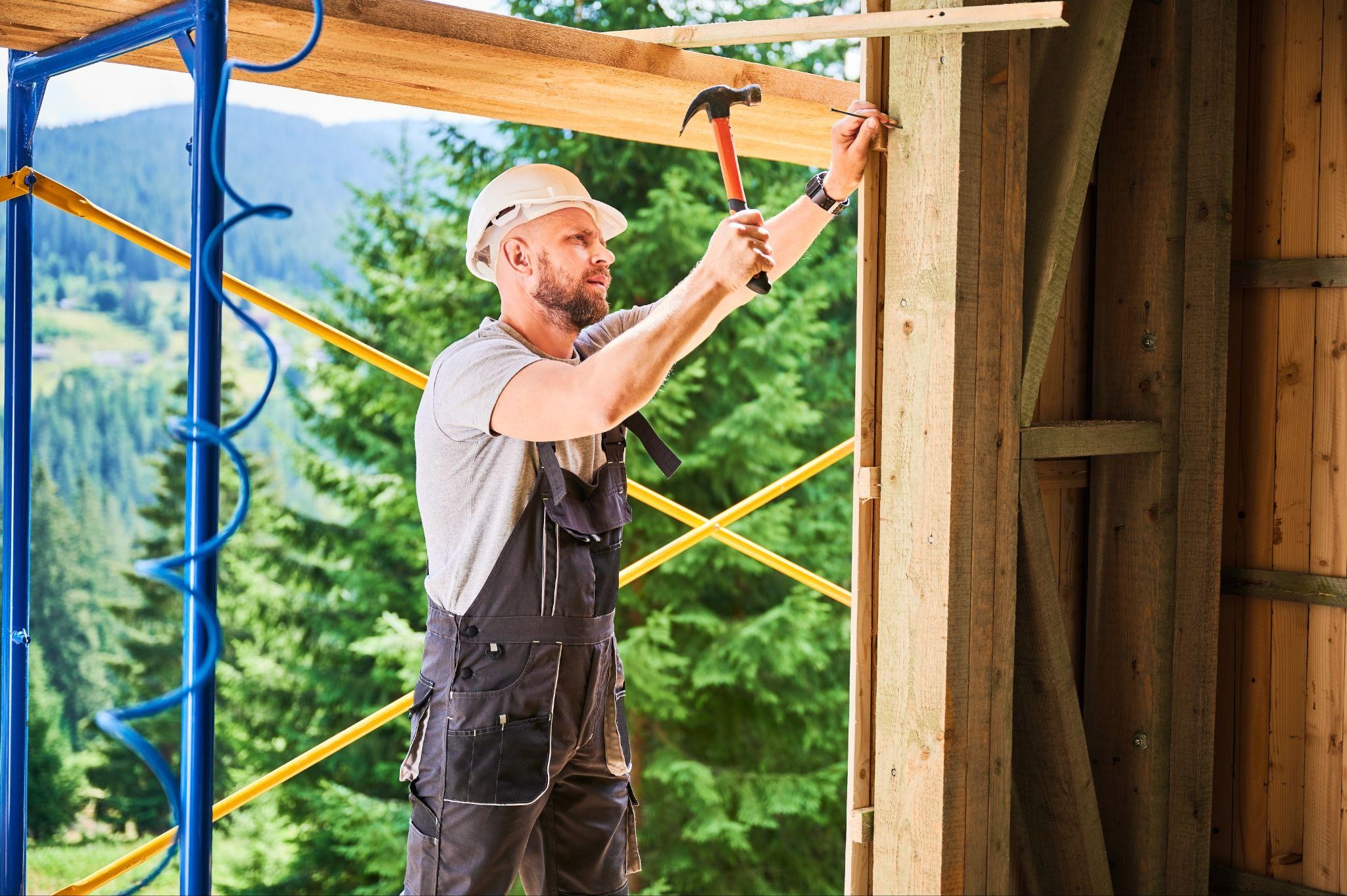 Contractor repairing wooden frame of a pole barn in New York, demonstrating structural reinforcement during barn restoration for safety compliance.