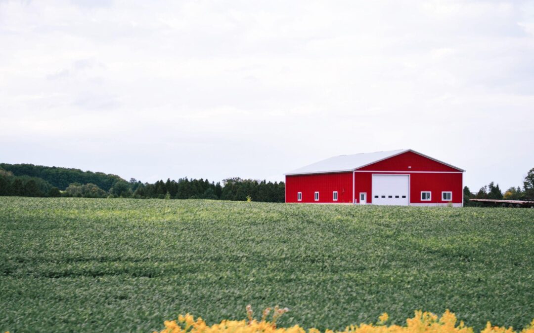Red barn with large sliding barn door styles on a New York farm surrounded by green fields.