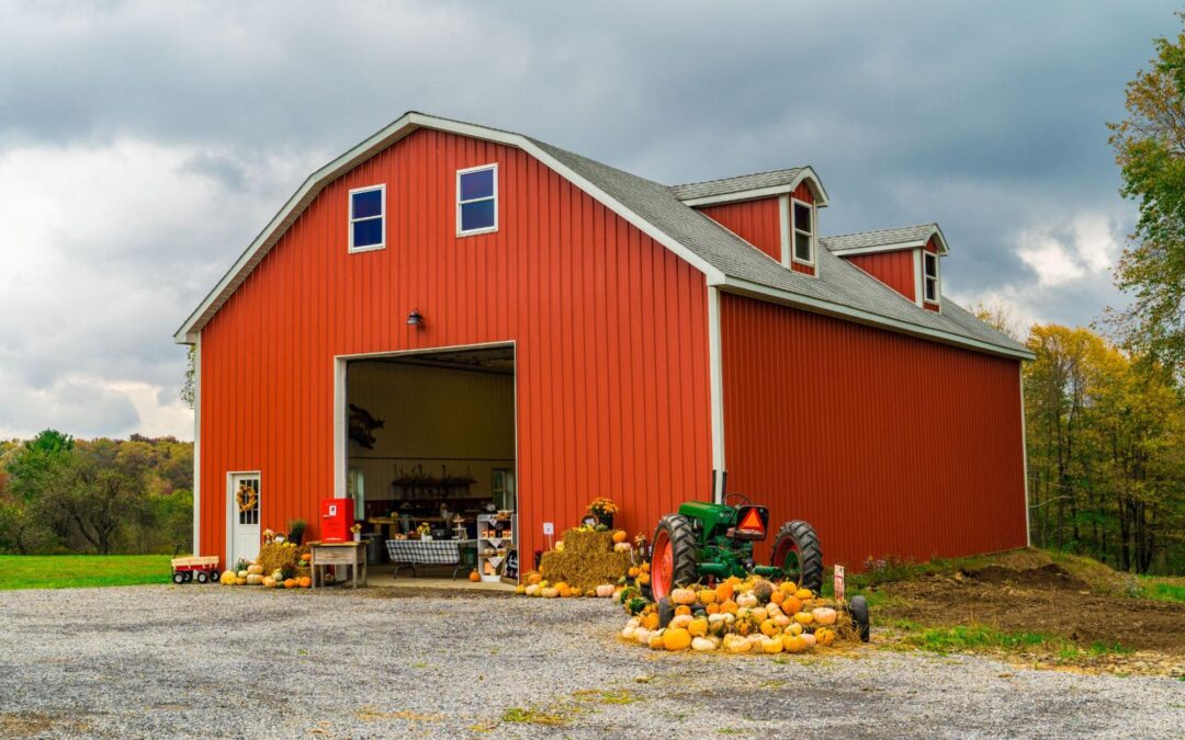 Red rural barn with vintage tractor and fall harvest display, showing a completed barn renovation that preserves classic design while supporting modern farm use.