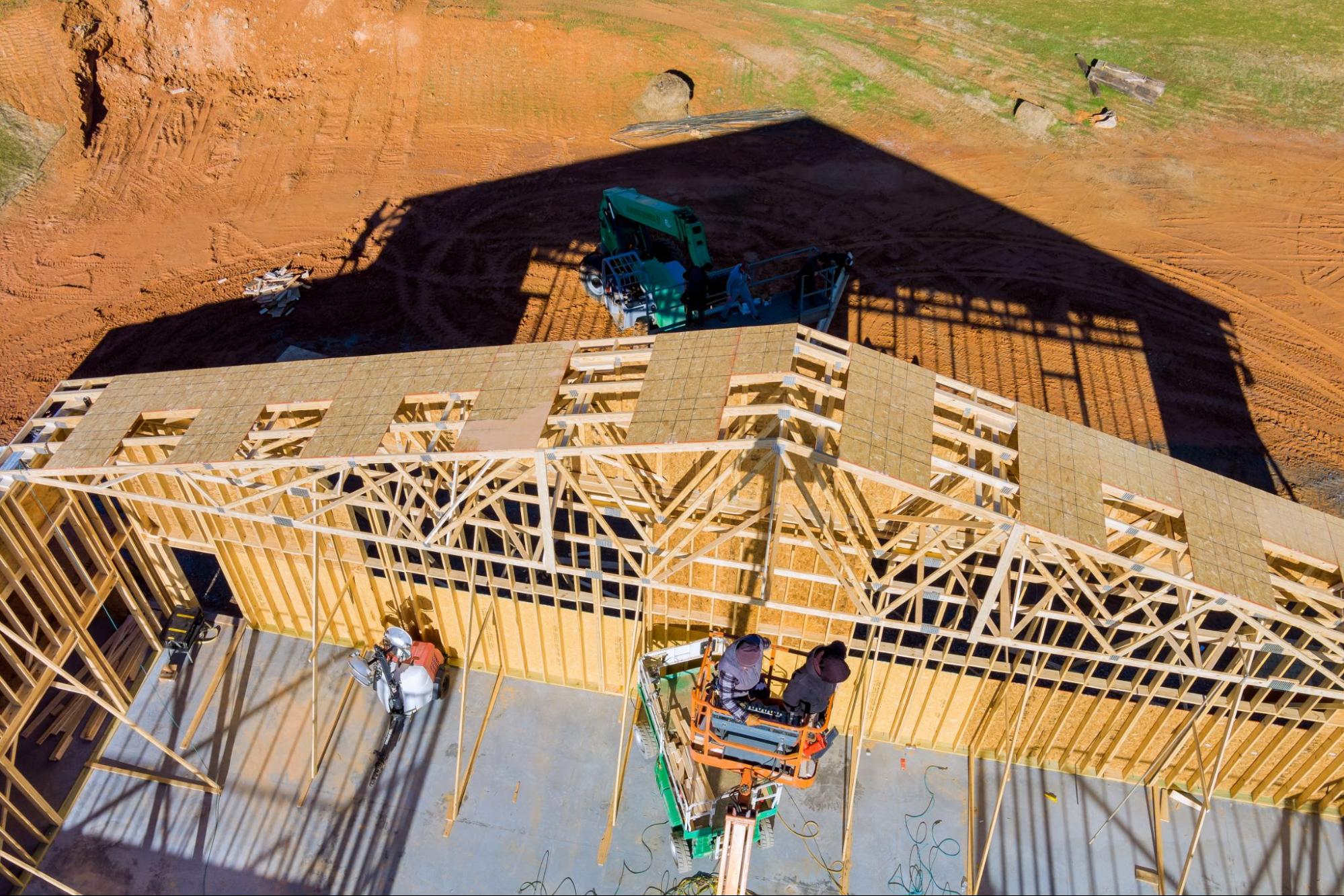 image5 Aerial view of pole barn construction crew installing roof trusses on wooden frame.