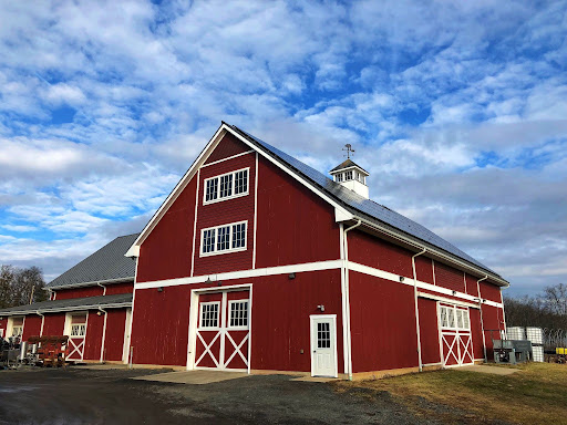 Large red barn with tall gable end, oversized doors, and a cupola, showing how barn size fits its use